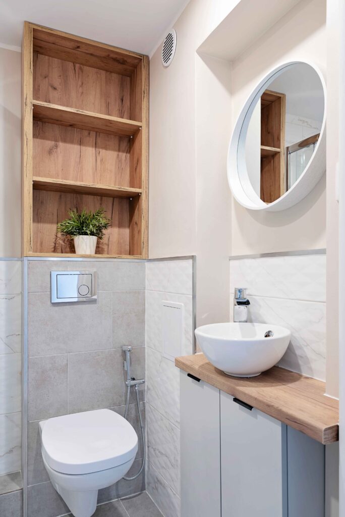 Half tiled bathroom with open shelving, mirror, and plant