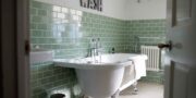 Bathroom with green metro tiles, roll top bath, chrome features.