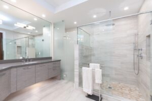 Modern wetroom with grey vanity unit, large mirror, chrome fixtures, and LED ceiling spotlights.