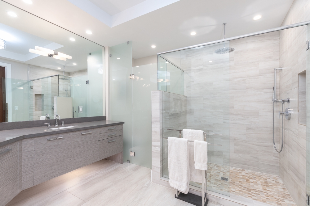 Modern wetroom with grey vanity unit, large mirror, chrome fixtures, and LED ceiling spotlights. 