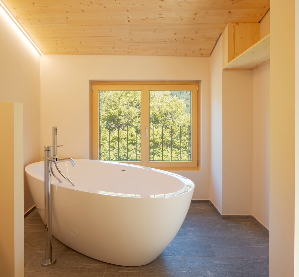 Modern bathroom with standalone bathtub and wooden ceiling.