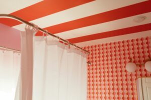 Red and white striped bathroom ceiling with patterned wallpaper and white shower curtain.