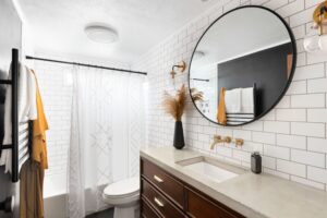 Modern bathroom with white tiles, concrete vanity top, large mirror, and white painted plaster ceiling.